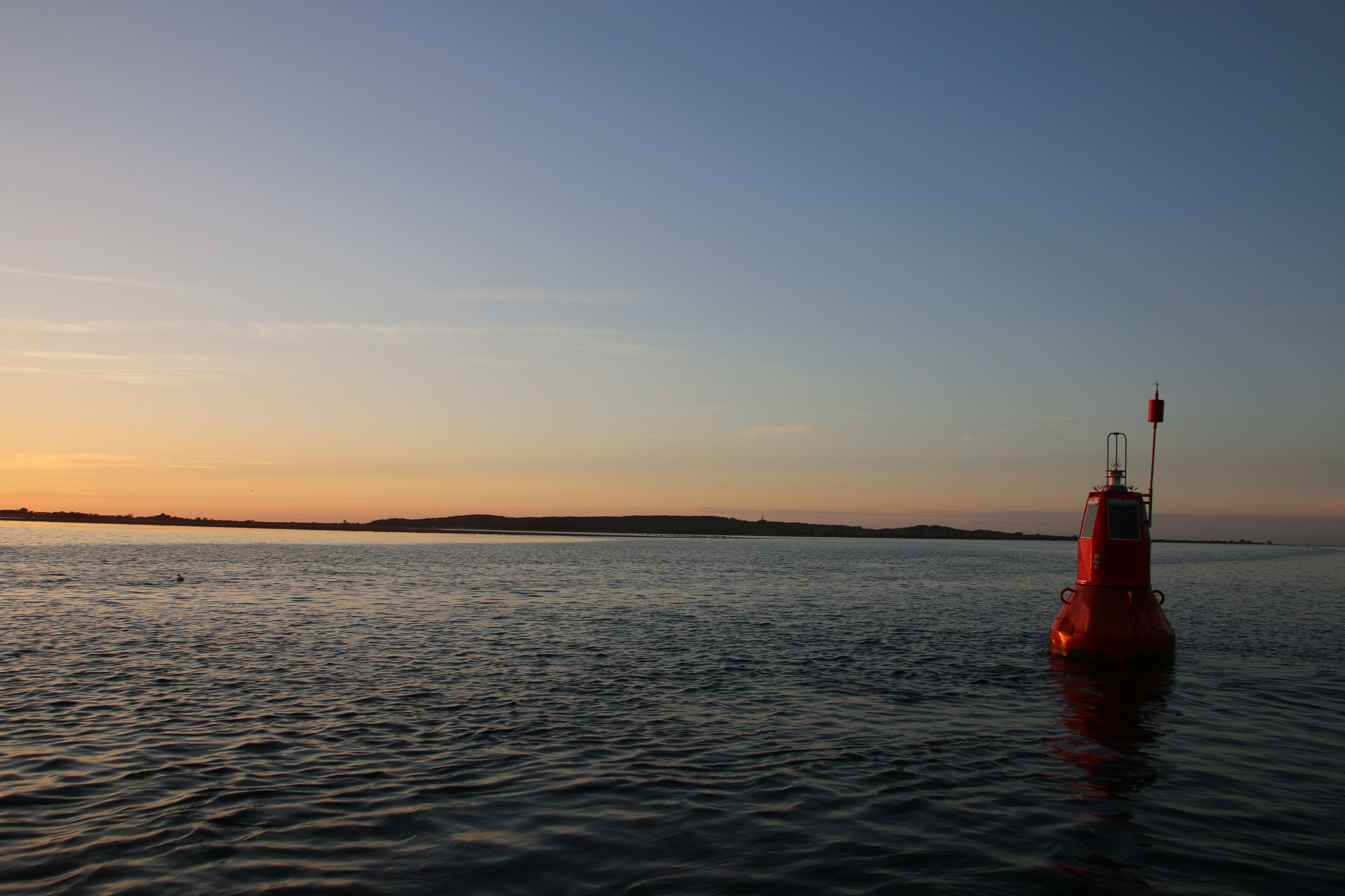 En bøje i roligt vand under solnedgang.