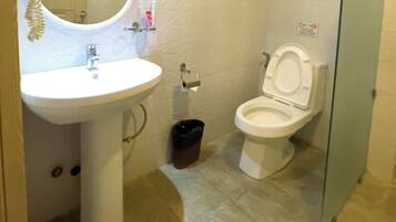 A bathroom with a white sink, toilet, and a trash bin.