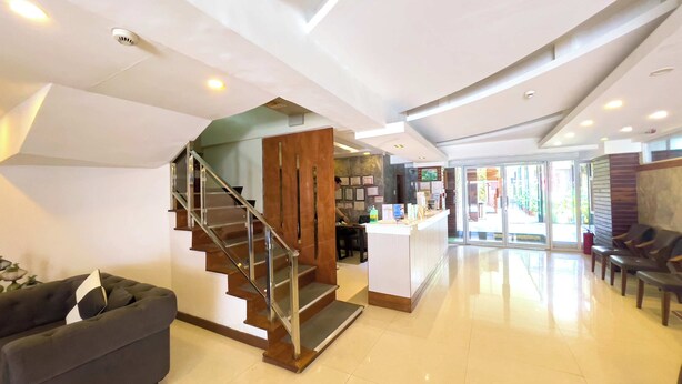 A modern hotel lobby with a staircase, a reception desk, and seating area. - Balibago Hotel (Angeles City)
