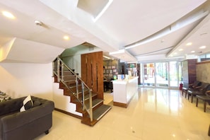 A modern hotel lobby with a staircase, a reception desk, and seating area. - Balibago Hotel (Angeles City)