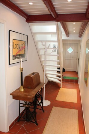 A staircase with a white railing, a framed poster on the wall, and a wooden table with a candle. - Romantic Frisian house on the East Frisian coast (Krummhörn)