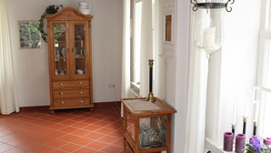 A room with a wooden cabinet, a small table with a lamp, and a window with candles. - Romantic Frisian house on the East Frisian coast (Krummhörn)