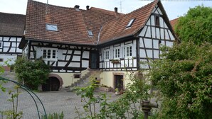 A traditional half-timbered house with a courtyard, a well-maintained garden, and a visible water spout. - Idyllic half-timbered house with a large garden and playground and orchard (Cleebourg)