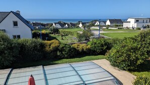 Zona residencial com vista clara para o mar, casas com telhados inclinados e um jardim bem cuidado.