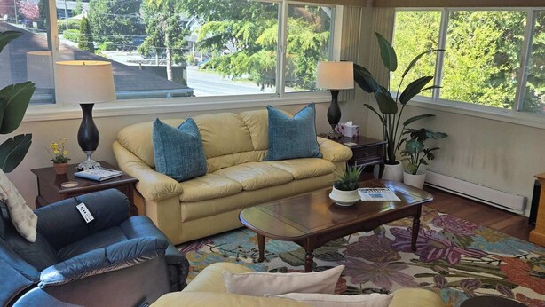 Una sala de estar con sofá, sillón, mesa de centro y televisor.