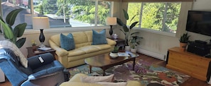 Ein Wohnzimmer mit Sofa, Sessel, Couchtisch und Fernseher.