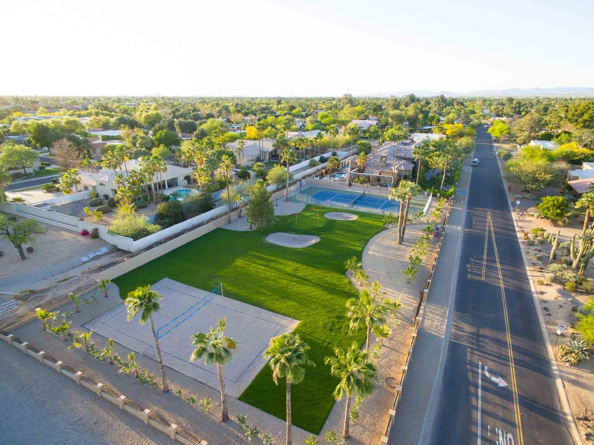 An aerial view of a residential area with houses, a tennis court, and a road.