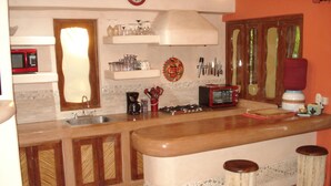 A kitchen with a central island, a microwave, a toaster, and various utensils. - Beautiful Pool Side Condo, Ground Level.  Close to Beach & Town Center   (zihuatanejo)