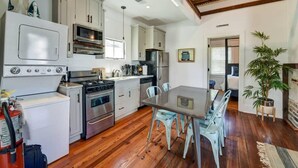A compact kitchen with modern appliances, a dining area with a table and chairs, and a staircase leading to an upper level. - Perfect 2bd Suite w. Porch, Near King Street! (Charleston)