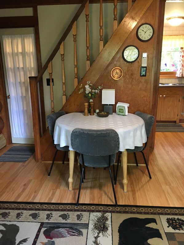 Cozy dining area with a round table set for four, featuring a vase with flowers, a salt and pepper set, and a decorative box.