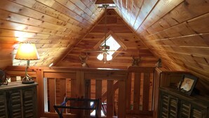 Un dormitorio acogedor en el ático, con paredes de madera y techo inclinado.