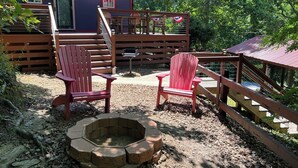 Una terraza con sillas Adirondack, un brasero y un paraguas rojo.