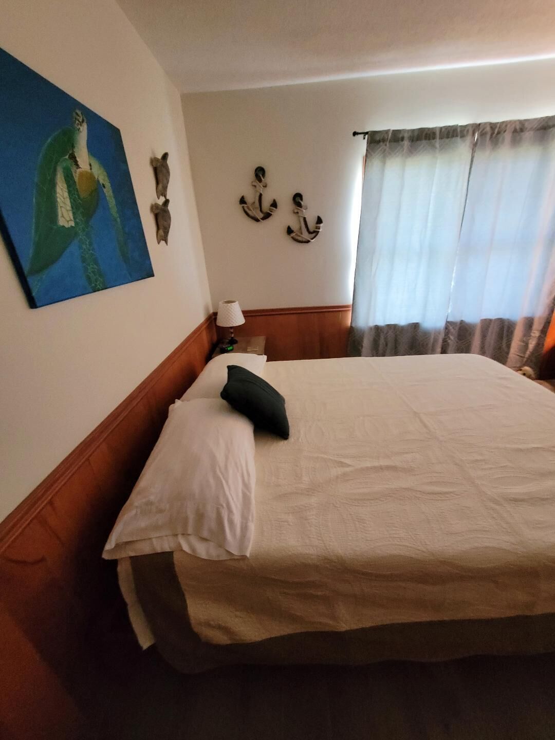 Una habitación de hotel con una cama grande, un cuadro en la pared y dos anclajes fijados a la pared.