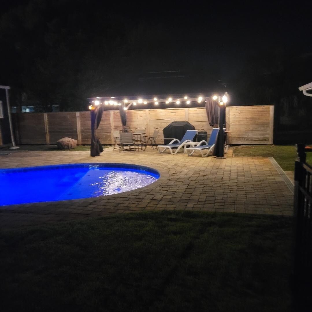 Un jardin avec une piscine, un espace barbecue et un coin salon extérieur.
