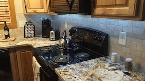 Una cocina con encimera de granito, estufa y armarios de madera.