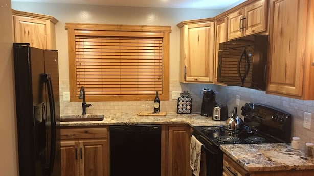 Una cocina con armarios de madera, un refrigerador negro, una estufa y un lavamanos.