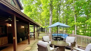 A covered outdoor deck with wicker furniture, a table, and an umbrella. - Spacious 4B-3B cabin-Stunning Views-Beautiful outdoor areas-By Fall Creek Falls (Spencer)