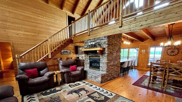 A spacious living area with a stone fireplace, wooden flooring, and a high wooden ceiling. - Spacious 4B-3B cabin-Stunning Views-Beautiful outdoor areas-By Fall Creek Falls (Spencer)