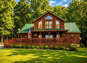 Une cabane en bois dotée d’un porche, entourée d’une pelouse bien entretenue et d’arbres.