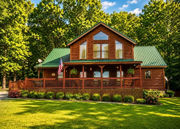 Une cabane en bois dotée d’un porche, entourée d’une pelouse bien entretenue et d’arbres.