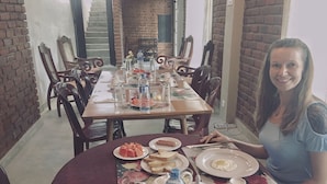 A dining area with a brick wall, wooden chairs, and a table set with plates of food, water bottles, and tea sets. - No17 Residence (Kandy)
