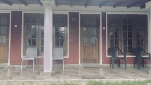 A covered porch with a tiled floor, wooden doors with glass panels, and two wicker chairs. - No17 Residence (Kandy)