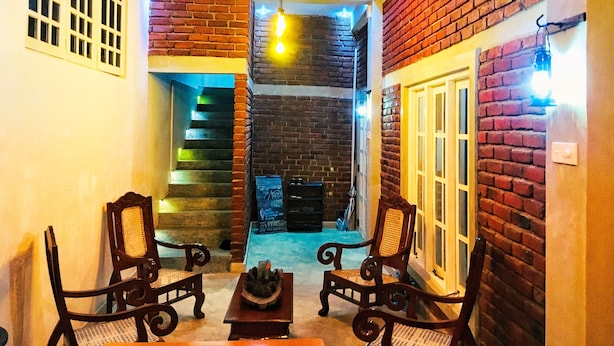 A cozy interior with a fireplace, two wooden chairs, a small table, and a staircase leading to another level. - No17 Residence (Kandy)