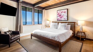 A bedroom with a wooden bed, a sofa, a TV, and a window with a view. - 7 Bedroom Oceanfront in Dillon Beach with spa (Dillon Beach)