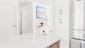 Eine moderne Küche mit weißen Schränken, einem Edelstahlkühlschrank und einer Holz Arbeitsplatte.