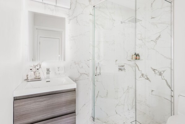 A modern bathroom with a marble wall, a glass shower enclosure, and a wooden vanity. - Moby House Aspen: A Curated Retreat w/ 2BR/2BA , AJAX Views
in the Aspen Core (Aspen)