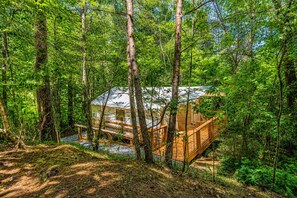 A wooden cabin surrounded by dense forest. - Glamorous Glamping Tent w/ A/C & Lodge Access Near Ocoee (Copperhill)