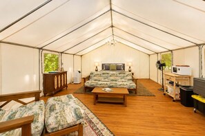 A tented accommodation with a bed, seating area, and a table. - Glamorous Glamping Tent w/ A/C & Lodge Access Near Ocoee (Copperhill)