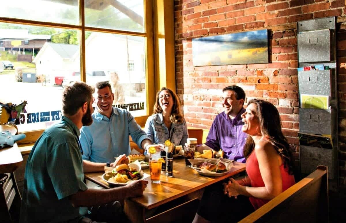 A group of people dining at a restaurant with a brick wall and large windows.