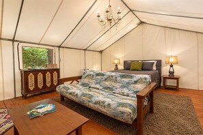 Una habitación con carpa, una cama, lámparas de noche, una mesa de madera y un armario.