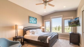 Une chambre à coucher avec un lit, une chaise, un téléviseur et un ventilateur de plafond.