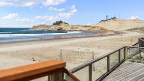 A beach with a wooden boardwalk leading to the shore, sandy dunes, and the ocean.