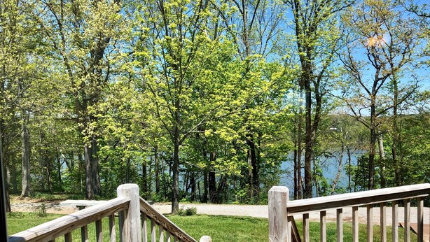 A wooden deck leading to a grassy area with a lake and trees in the background. - Beautiful Vacation Home on Lake Cumberland, Monticello, KY (Monticello)