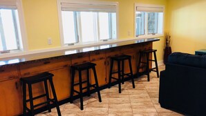 A kitchen with a bar area, four stools, and a sofa. - Beautiful Vacation Home on Lake Cumberland, Monticello, KY (Monticello)