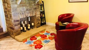 A stone fireplace with candles, a red leather chair, and a colorful rug in a room with yellow walls. - Beautiful Vacation Home on Lake Cumberland, Monticello, KY (Monticello)