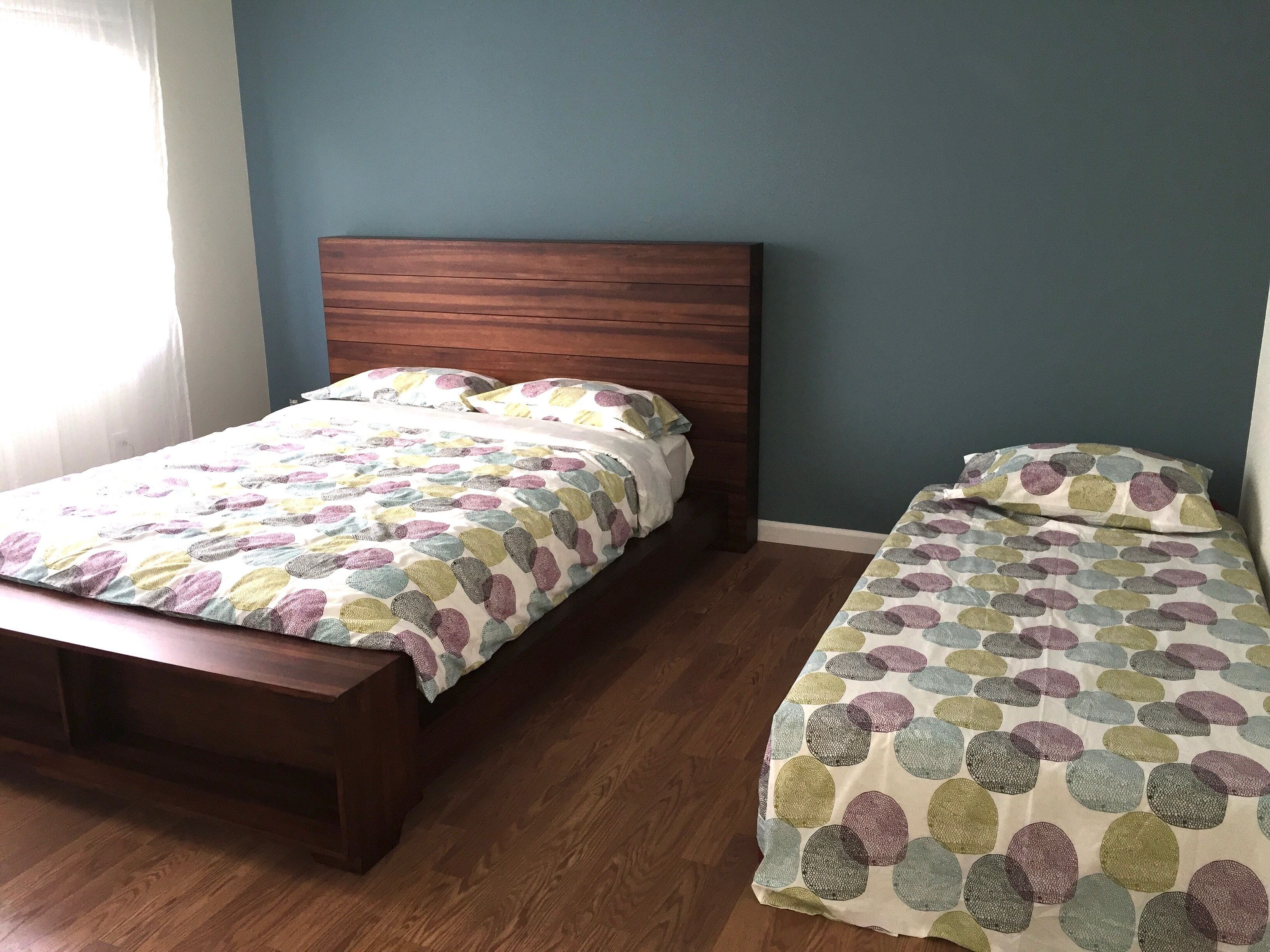 Ein Schlafzimmer mit einem hölzernen Bett, einer passenden Bank und einer gemusterten Bettdecke.