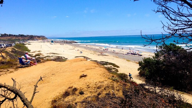 A beach with people, a lifeguard tower, and a rocky shoreline.