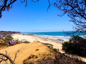 A beach with people, a lifeguard tower, and a rocky shoreline. - LOWER UNIT-  STEPS TO THE BEACH, WALK TO VILLAGE (Carlsbad)