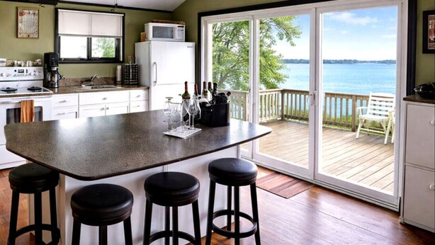 Una cocina con una isla grande, taburetes de bar, vista al océano y un letrero que dice "BEACH".