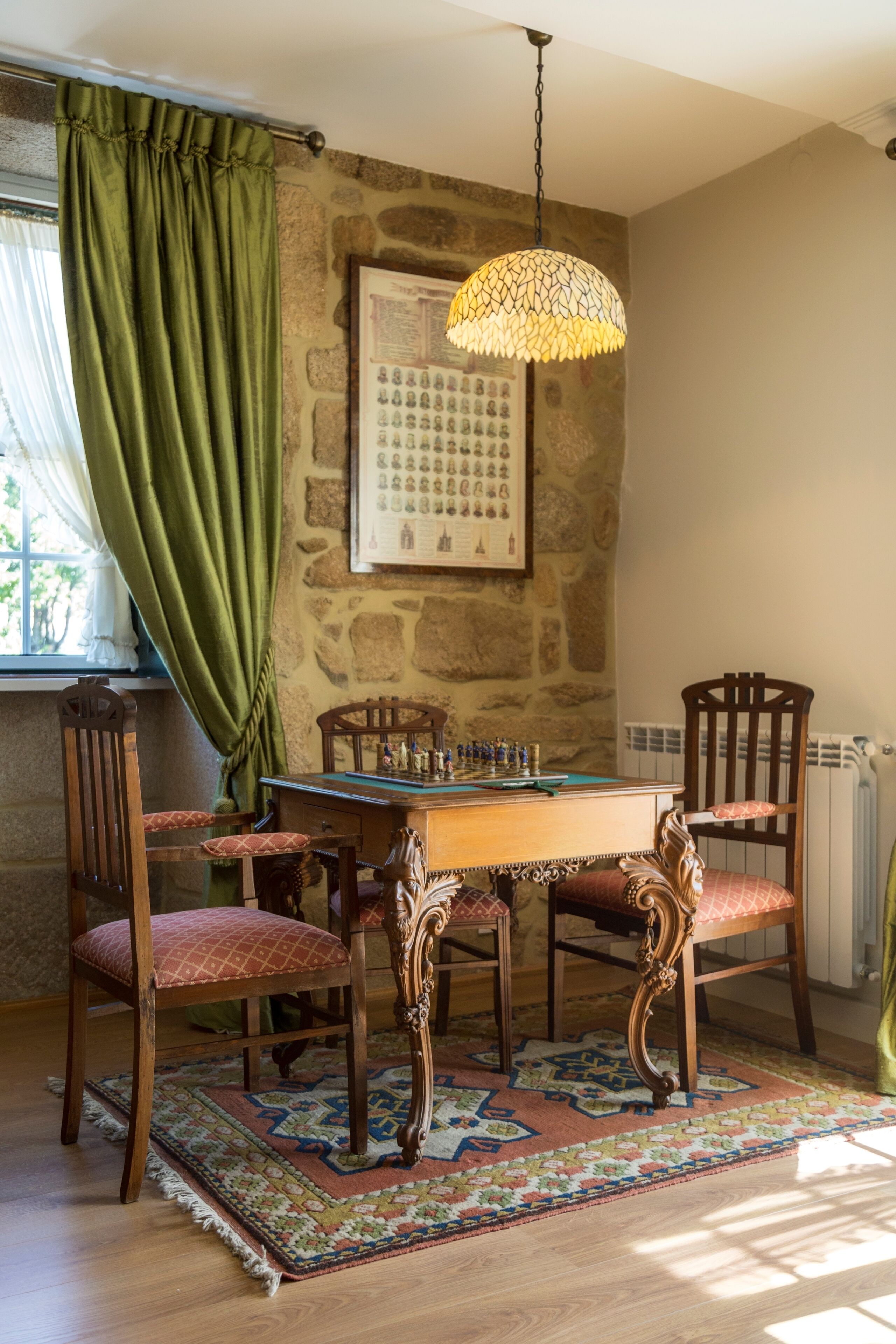 Zona pranzo con tavolo in legno, sedie e tappeto decorato.