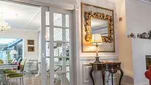 Una habitación con comedor, un espejo grande y una lámpara sobre una mesa.