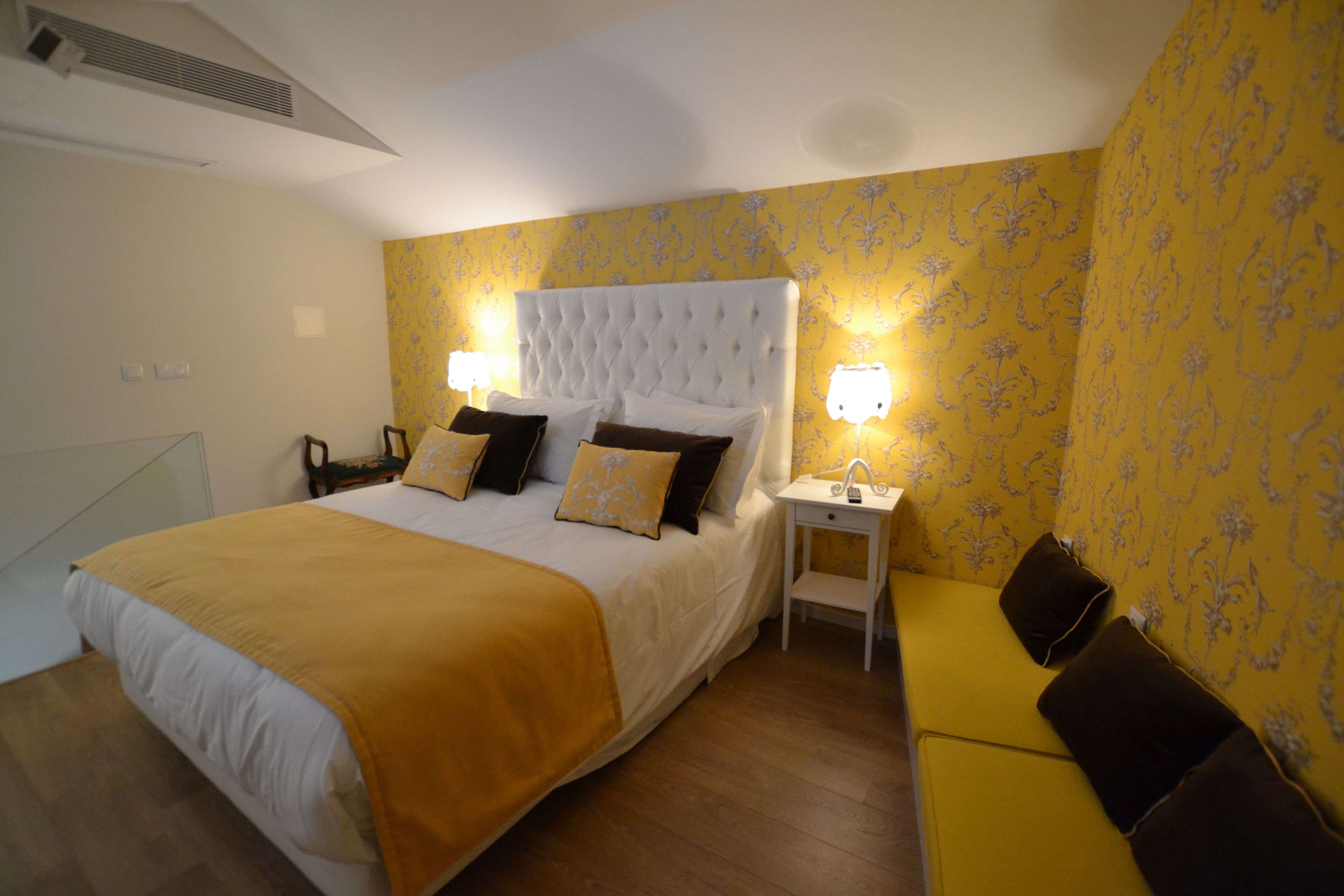 A hotel room with a large bed, bedside tables, a nightstand, and a sofa.