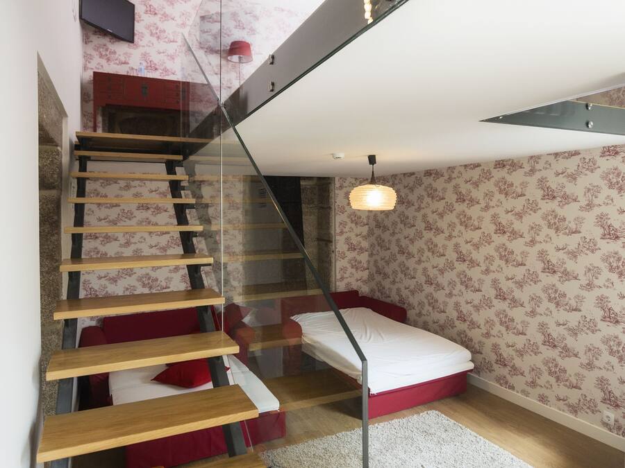 A modern staircase with glass railings, wooden steps, and a red accent wall.