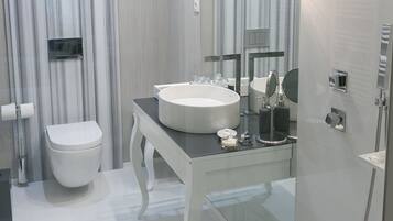 Un baño moderno con cabina de ducha de vidrio, un lavamanos blanco y un tocador con espejo.