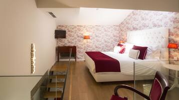 Une chambre à coucher avec un lit, des lampes de chevet, une télévision et un escalier.
