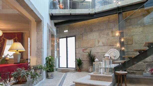 Un vestíbulo con pared de piedra, una escalera y plantas en macetas.